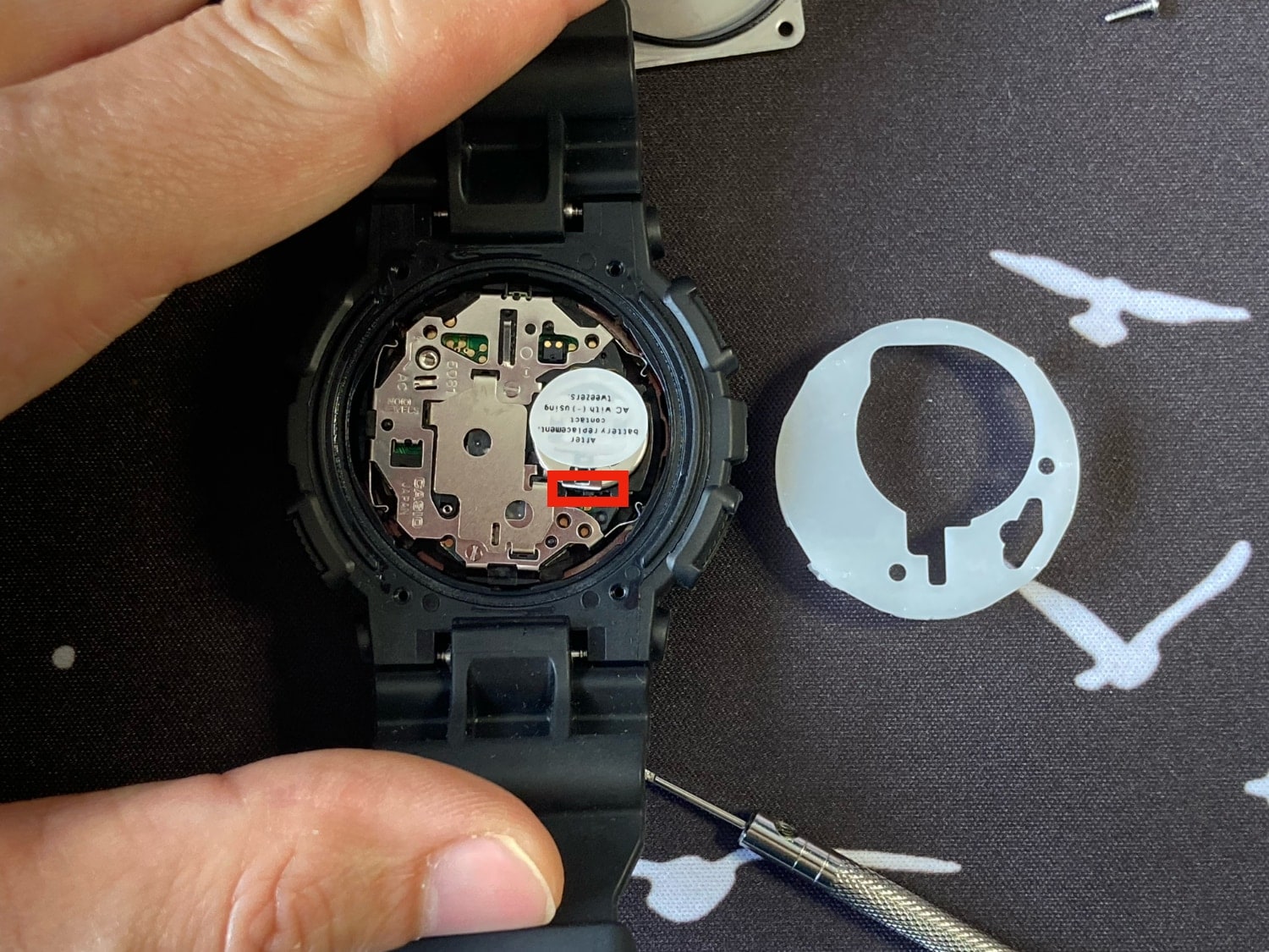 Guía para cambiar la pila del Casio G-Shock GA-100: tienes que tirar en esta parte con unas pinzas para solar la parte metálica que sujeta la pila. 
