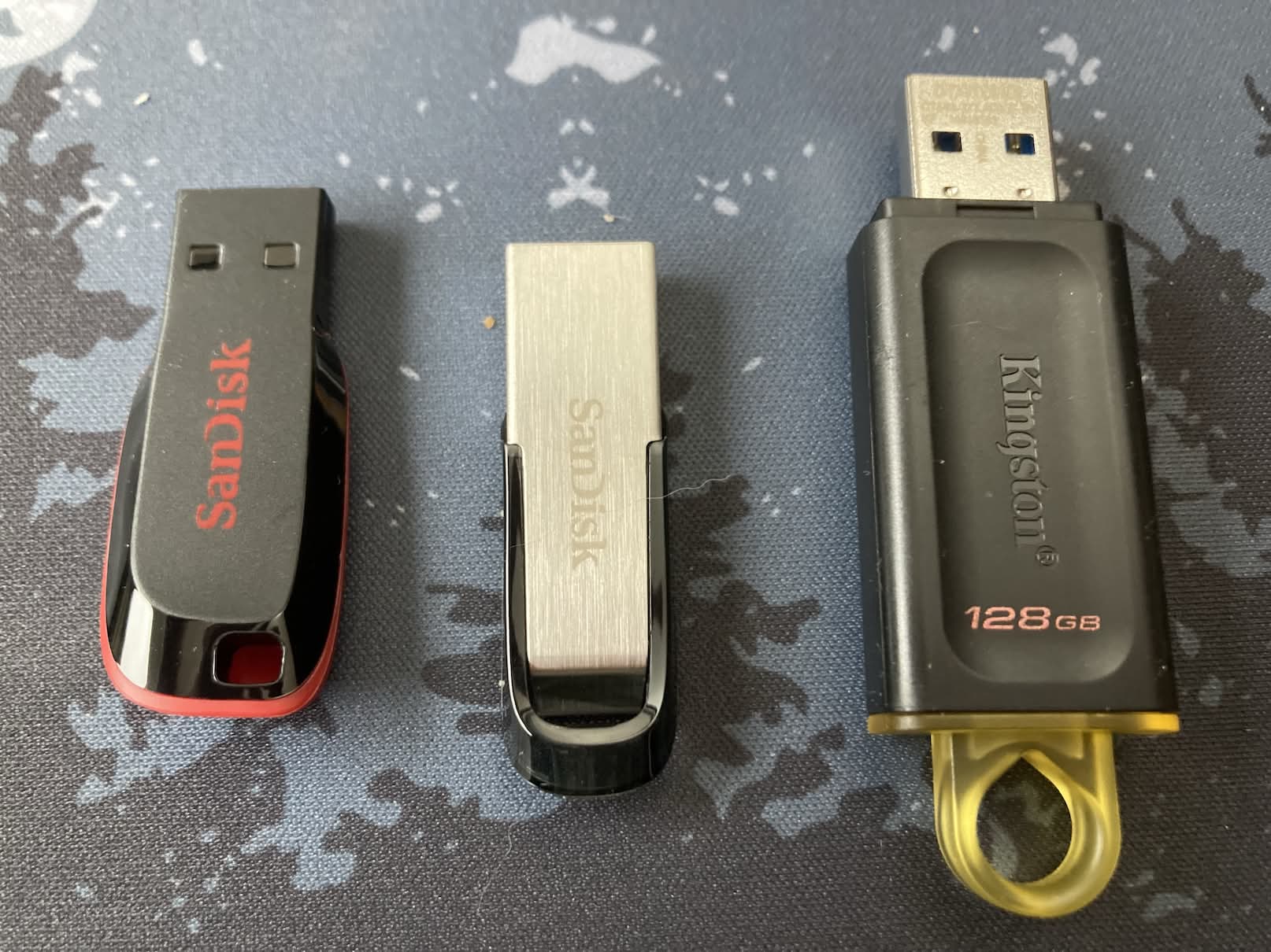 Tres memorias USB de cerca: Kingston DataTraveler Exodia DTX/128GB USB 3.2 Gen 1, Cruzer Blade USB 2.0 de 64 GB y Sandisk Ultra Flair Memoria flash USB 3.0 de 64