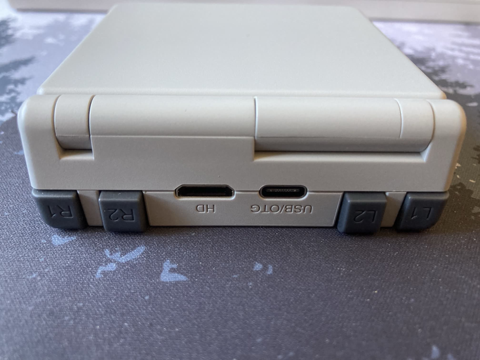 ANBERNIC RG 34XXSP: lateral trasero con botones R y L, conexión HDMI mini y USB.